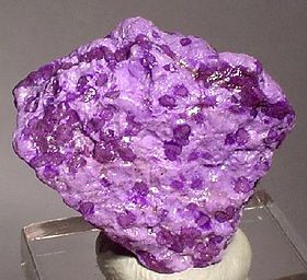 Vibrant purple sugilite mineral sample against dark background.